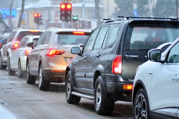 Cars standing in row in traffic jam on city street on slippery snowy road in winter