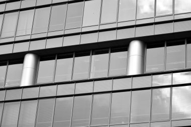 Cam pencerede yansıyan gökyüzü ve bulut ile modern bina. Siyah beyaz.