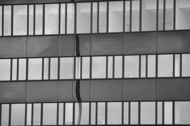 Cam pencerede yansıyan gökyüzü ve bulut ile modern bina. Siyah beyaz.