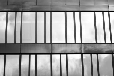 Cam pencerede yansıyan gökyüzü ve bulut ile modern bina. Siyah beyaz.