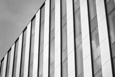 Cam pencerede yansıyan gökyüzü ve bulut ile modern bina. Siyah beyaz.