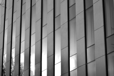 Cam pencerede yansıyan gökyüzü ve bulut ile modern bina. Siyah beyaz.