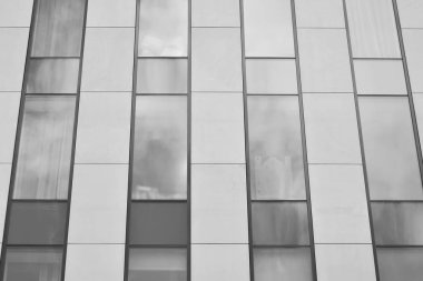 Cam pencerede yansıyan gökyüzü ve bulut ile modern bina. Siyah beyaz.