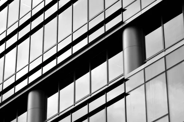 Cam pencerede yansıyan gökyüzü ve bulut ile modern bina. Siyah beyaz.