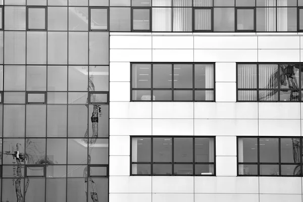 Modern building with reflected sky and cloud in glass window. Black and white.