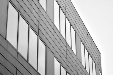 Cam pencerede yansıyan gökyüzü ve bulut ile modern bina. Siyah beyaz.