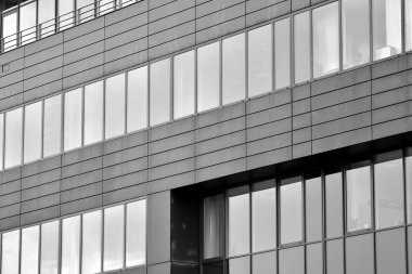 Cam pencerede yansıyan gökyüzü ve bulut ile modern bina. Siyah beyaz.