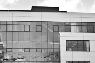 Cam pencerede yansıyan gökyüzü ve bulut ile modern bina. Siyah beyaz.