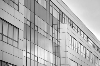 Cam pencerede yansıyan gökyüzü ve bulut ile modern bina. Siyah beyaz.