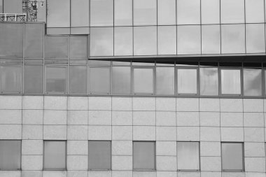 Cam pencerede yansıyan gökyüzü ve bulut ile modern bina. Siyah beyaz.