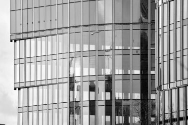 Cam pencerede yansıyan gökyüzü ve bulut ile modern bina. Siyah beyaz.