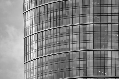 Cam pencerede yansıyan gökyüzü ve bulut ile modern bina. Siyah beyaz.