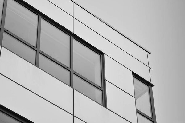 Modern building with reflected sky and cloud in glass window. Black and white.