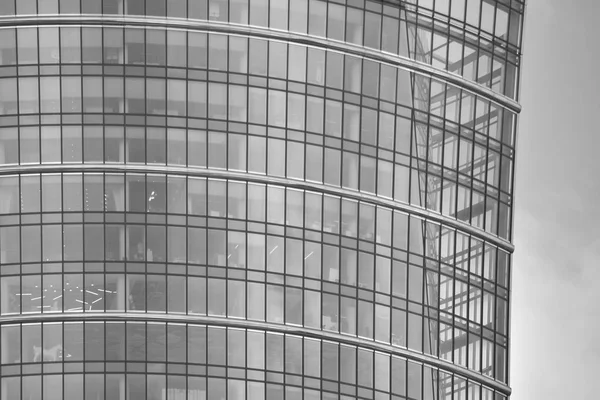 Modern building with reflected sky and cloud in glass window. Black and white.