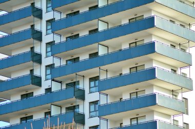 Mavi gökyüzü olan güneşli bir günde modern apartman binaları. Modern bir apartmanın cephesi