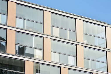 Mavi gökyüzü olan güneşli bir günde modern apartman binaları. Modern bir apartmanın cephesi