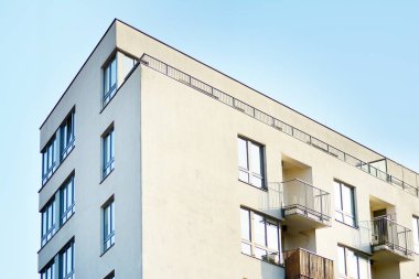 Mavi gökyüzü olan güneşli bir günde modern apartman binaları. Modern bir apartmanın cephesi