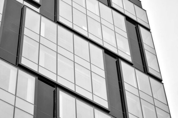 Facade fragment of a modern office building. Exterior of glass wall with abstract texture. Black and white.