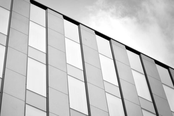Facade fragment of a modern office building. Exterior of glass wall with abstract texture. Black and white.