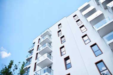 Mavi gökyüzü olan güneşli bir günde modern apartman binaları. Modern bir apartmanın cephesi