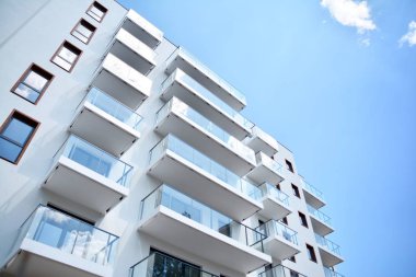 Mavi gökyüzü olan güneşli bir günde modern apartman binaları. Modern bir apartmanın cephesi