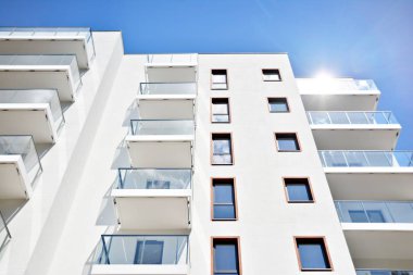 Mavi gökyüzü olan güneşli bir günde modern apartman binaları. Modern bir apartmanın cephesi