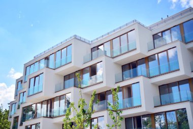 Mavi gökyüzü olan güneşli bir günde modern apartman binaları. Modern bir apartmanın cephesi