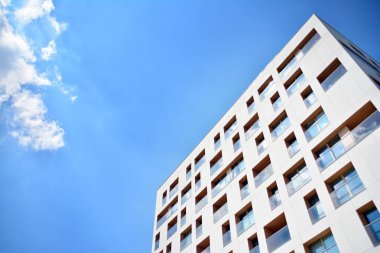 Mavi gökyüzü olan güneşli bir günde modern apartman binaları. Modern bir apartmanın cephesi