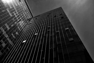 Geceleri gökdelenin siyah cam silueti. Gökdelenlerin kasvetli şehri. Siyah beyaz.