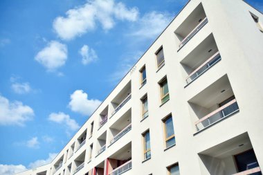 Mavi gökyüzü ve bulutlar ile modern daire binası. Modern çok katlı lüks konut konsepti.