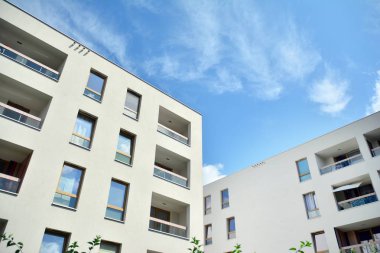 Mavi gökyüzü ve bulutlar ile modern daire binası. Modern çok katlı lüks konut konsepti.