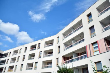 Mavi gökyüzü ve bulutlar ile modern daire binası. Modern çok katlı lüks konut konsepti.