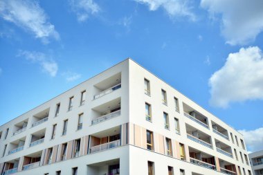 Mavi gökyüzü ve bulutlar ile modern daire binası. Modern çok katlı lüks konut konsepti.