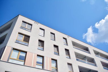 Mavi gökyüzü ve bulutlar ile modern daire binası. Modern çok katlı lüks konut konsepti.