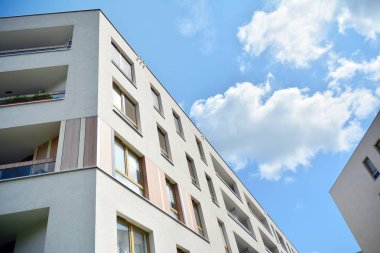 Mavi gökyüzü ve bulutlar ile modern daire binası. Modern çok katlı lüks konut konsepti.