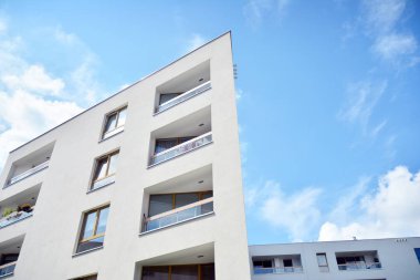 Mavi gökyüzü ve bulutlar ile modern daire binası. Modern çok katlı lüks konut konsepti.