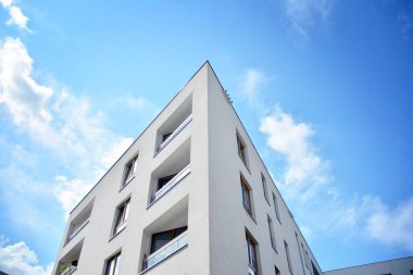 Mavi gökyüzü ve bulutlar ile modern daire binası. Modern çok katlı lüks konut konsepti.