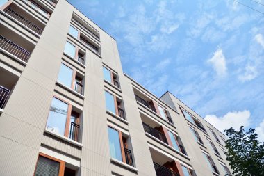 Gündüz gözüyle modern yerleşim yerinin dış tarafında. Mavi gökyüzü olan güneşli bir günde modern apartman binaları. Modern bir apartmanın cephesi