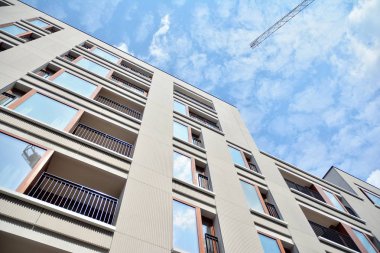 Gündüz gözüyle modern yerleşim yerinin dış tarafında. Mavi gökyüzü olan güneşli bir günde modern apartman binaları. Modern bir apartmanın cephesi