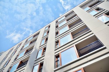 Gündüz gözüyle modern yerleşim yerinin dış tarafında. Mavi gökyüzü olan güneşli bir günde modern apartman binaları. Modern bir apartmanın cephesi