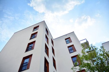 Gündüz gözüyle modern yerleşim yerinin dış tarafında. Mavi gökyüzü olan güneşli bir günde modern apartman binaları. Modern bir apartmanın cephesi