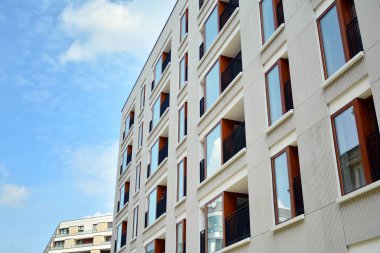 Gündüz gözüyle modern yerleşim yerinin dış tarafında. Mavi gökyüzü olan güneşli bir günde modern apartman binaları. Modern bir apartmanın cephesi