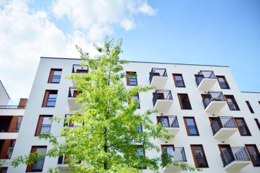 Gündüz gözüyle modern yerleşim yerinin dış tarafında. Mavi gökyüzü olan güneşli bir günde modern apartman binaları. Modern bir apartmanın cephesi