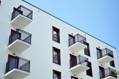 Gündüz gözüyle modern yerleşim yerinin dış tarafında. Mavi gökyüzü olan güneşli bir günde modern apartman binaları. Modern bir apartmanın cephesi