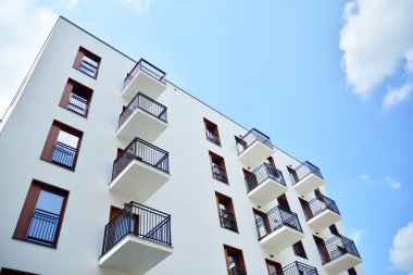 Gündüz gözüyle modern yerleşim yerinin dış tarafında. Mavi gökyüzü olan güneşli bir günde modern apartman binaları. Modern bir apartmanın cephesi