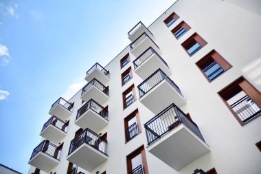 Gündüz gözüyle modern yerleşim yerinin dış tarafında. Mavi gökyüzü olan güneşli bir günde modern apartman binaları. Modern bir apartmanın cephesi