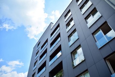 Gündüz gözüyle modern yerleşim yerinin dış tarafında. Mavi gökyüzü olan güneşli bir günde modern apartman binaları. Modern bir apartmanın cephesi