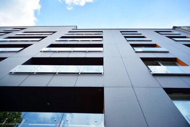 Gündüz gözüyle modern yerleşim yerinin dış tarafında. Mavi gökyüzü olan güneşli bir günde modern apartman binaları. Modern bir apartmanın cephesi