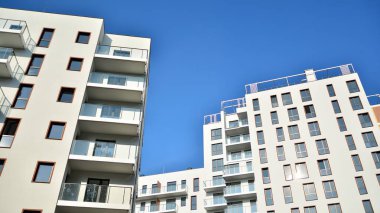 Gündüz gözüyle modern yerleşim yerinin dış tarafında. Mavi gökyüzü olan güneşli bir günde modern apartman binaları. Modern bir apartmanın cephesi