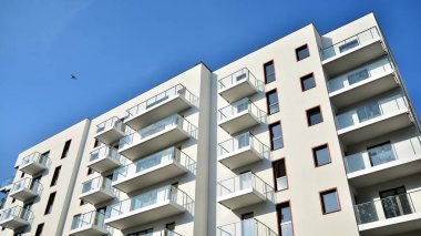 Gündüz gözüyle modern yerleşim yerinin dış tarafında. Mavi gökyüzü olan güneşli bir günde modern apartman binaları. Modern bir apartmanın cephesi